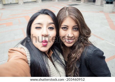 two latin girls taking a selfie outdoors
