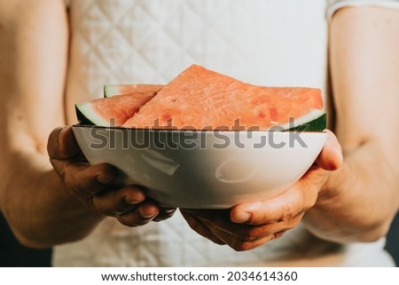 Close up of an old waitress offers and holds a watermelon in a bowl, fruits, healthy life, good eating, mediterranean concepts, copy space, vertical image