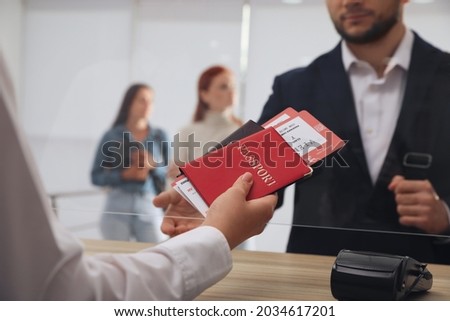 Agent giving passports with tickets to client at check-in desk in airport, closeup Royalty-Free Stock Photo #2034617201