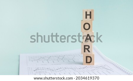 word HOARD with wood building blocks, light green background. document with numbers on background, business concept. space for text in left. front view