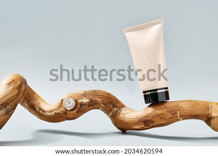 Tube of BB or CC cream on wooden snag on pastel gray background. Presentation stage for cosmetic product advertising. Eco-bio cosmetics concept. Beauty product promotion trendy minimalist mockup. Royalty-Free Stock Photo #2034620594