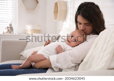 Young mother with her cute baby on sofa at home