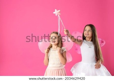 Cute little girls in fairy costumes with wings and magic wand on pink background. Space for text