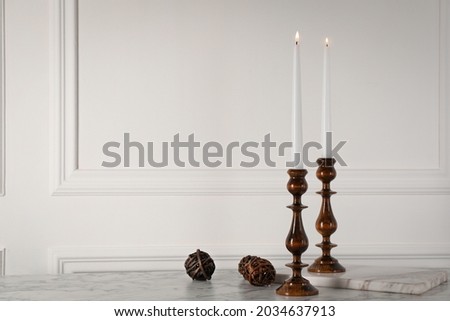 Elegant candlesticks with burning candles on white marble table. Space for text Royalty-Free Stock Photo #2034637913