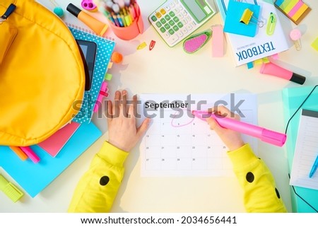 Back to school. Upper view of modern child with workbooks, stationary, textbook, september calendar and backpack at white table at home.