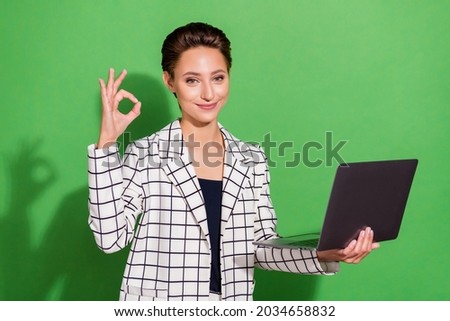 Photo of charming shiny young lady wear plaid outfit spectacles holding modern device showing okey isolated green color background