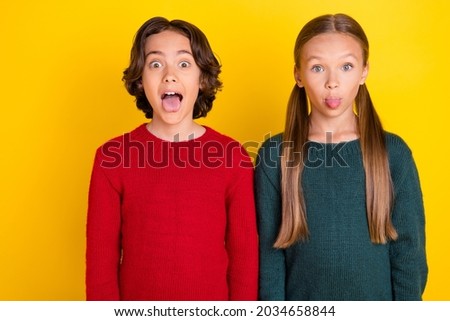 Portrait of attractive funny cheerful trendy couple grimacing fooling isolated over bright yellow color background