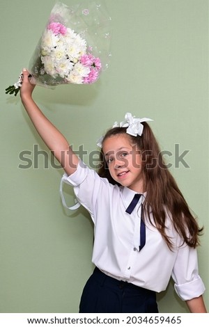 Portrait of  pretty girl with white bows in her hair and with bouquet of flowers in her hands. The first day of school. Back to school. Knowledge Day