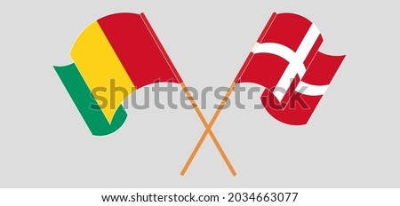 Crossed and waving flags of Guinea and Denmark