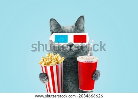 Funny hipster cat in 3D stereo glasses eating popcorn and a drinks coke at the movies on a blue background. 