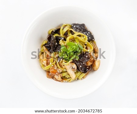 Asian wheat wok noodles with mushrooms - shiitake, porcini mushrooms, champignons, honey agarics - with sesame seeds, green onions, Asian sauce, served in a white ceramic bowl on a white background