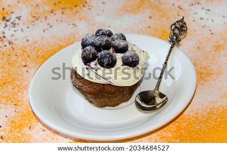 homemade cupcake, cupcake sprinkled with powdered blueberries, cream cake sprinkled with chocolate, on an orange background. selective focus