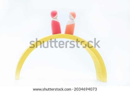 Wooden people of different colors. Objects in abstract meanings on team, life and many other subjects. A yellow rainbow..