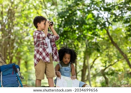 boy and girl African American ethnicity holding binoculars look at side view in the park, backpack adventure summer holiday on weekend concept 