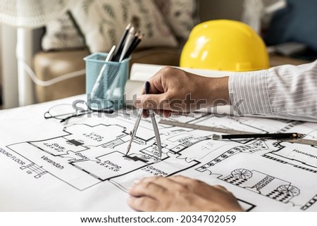 Architects use compasses to write on the blueprints of the houses, designing the buildings according to the standards and the law, designing the houses according to the needs of the residents. Royalty-Free Stock Photo #2034702059