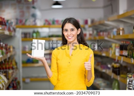 young woman showing product at super market Royalty-Free Stock Photo #2034709073