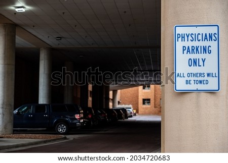 Physician parking sign posted outside of garage and hospital entrance