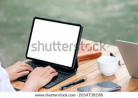 Cropped shot of woman hands typing on tablet keyboard while working outdoors, mock up blank screen for product display or graphic design.