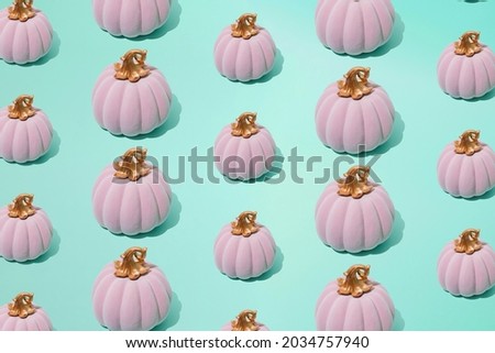 Arranged small and big pink Halloween fairy tale pumpkin on seafoam mint green color background. Minimal design and pattern.