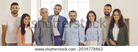 Group portrait of happy business professionals and colleagues. Company website banner with team of young and mature people standing in office, looking at camera and smiling
