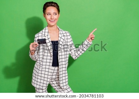 Photo of impressed sweet young lady wear plaid outfit pointing empty space holding credit card isolated green color background