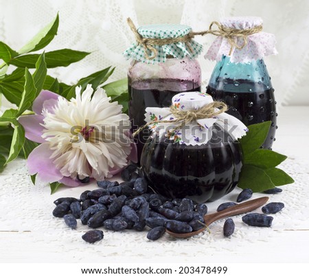 Three jam jars with honeysuckle berries and peony flower