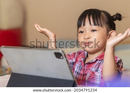 Portrait image of 3-4 years old preschool kid. Happy Asian child girl using and touching smart pad or tablet for do her homework and online learning (E-learning). Back to shool, Study frome home.