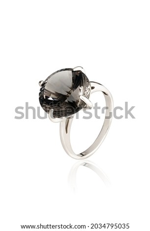 Silver ring with a black stone located diagonally with reflection on a white background