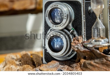 Vintage two lens photo camera with Hourglass on wooden background. An idea of old camera and memory, time Nostalgia.