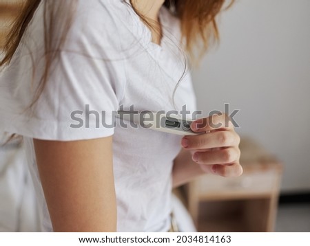 woman in white t-shirt hold thermometer armpit health temperature