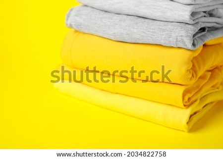 Stack of stylish clothes on color background