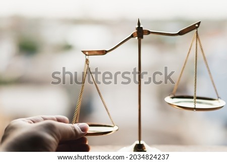 Tip the scales of justice concept as a the hand of a person illegally influencing the legal system for an unfair advantage. Royalty-Free Stock Photo #2034824237