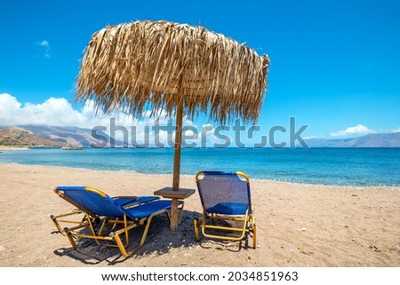 View to sun loungers and straw parasol on a beach. Kissamos, Crete, Greece Royalty-Free Stock Photo #2034851963