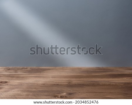 Empty wooden table top for product presentation with beam of light on background