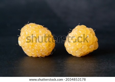 yellow raspberries in a cup on black background