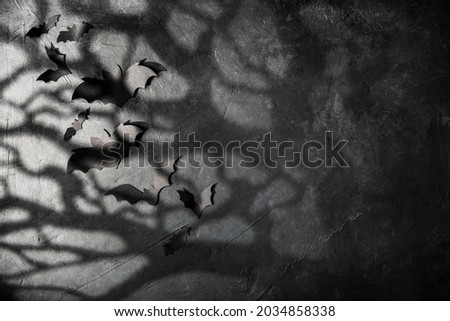 halloween and decoration concept - black paper bats, moonlight and scary trees shadows background
