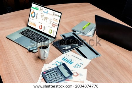 Top view mock up sales summary slide show presentation on display laptop with calculator and paperwork on table in meeting room