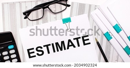 On the desktop are reports, documents, glasses, a calculator, a pen and paper with the text ESTIMATE. Business concept