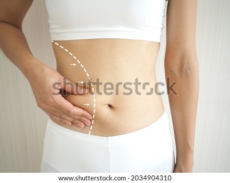 Young woman abdomen with marks drawn on skin, plastic surgery, beauty standards. closeup photo, blurred.