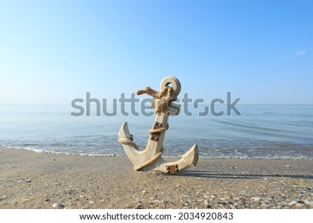 Wooden anchor with rope on sand near sea