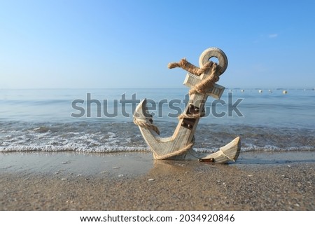 Wooden anchor with rope on sand near sea. Space for text Royalty-Free Stock Photo #2034920846