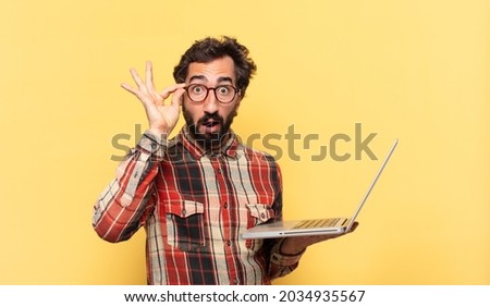 young crazy bearded man surprised expression and a laptop