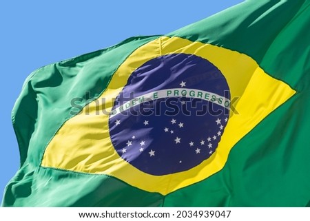 detail of Brazil flag fluttering in the blue sky. Translation: order and progress. proclamation of the Republic. proclamação da república Royalty-Free Stock Photo #2034939047