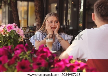 Young woman having boring date with guy in outdoor cafe Royalty-Free Stock Photo #2034957218