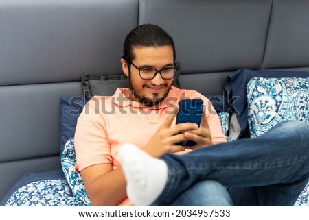 latino man in bed typing in the smart phone