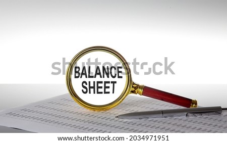 Inscription BALANCE SHEET on the magnifying glass with chart and pen