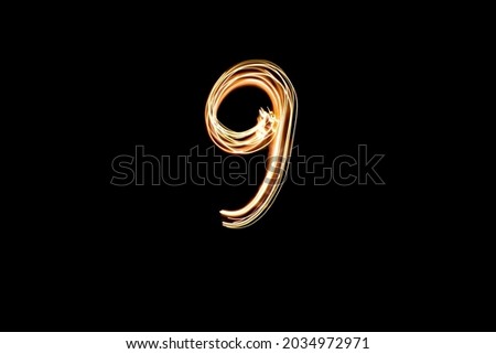 Number 9, long exposure photo of gold lights, light painting. Number nine on the black background.
