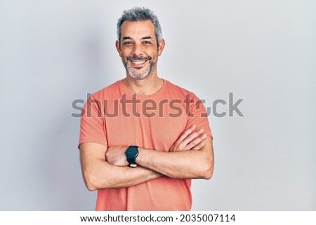 Handsome middle age man with grey hair wearing casual t shirt happy face smiling with crossed arms looking at the camera. positive person. 