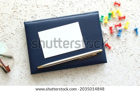 Business card lying on a blue notebook next to the glasses. Business concept.