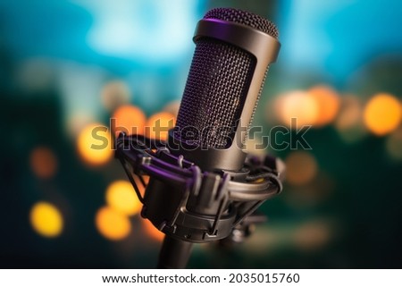 Professional studio microphone on blurred bokeh lights background for recording music, voice, lectures, storytelling, podcasts, sound, stand-up show or karaoke song